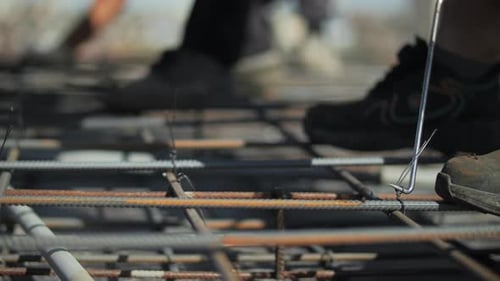 Worker Tying Steel Rebar Reinforcement at Construction Site