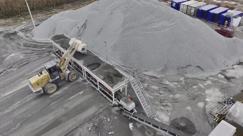 Baggerlader gießt Kies in die Sortiermaschine in der Gesteinsgrube