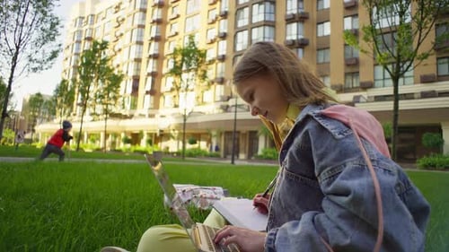 Student Studying Outdoors with Laptop and Notebook