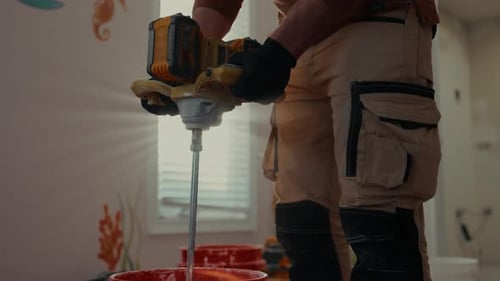 POV of Worker Mixing Construction Mortar in Red Bucket Using a Power Mixer Renovation Work Building