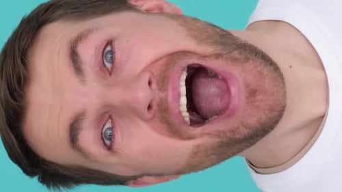 Closeup of a Happy Man Yelling at the Camera in a Studio on a Blue Background Vertical Video