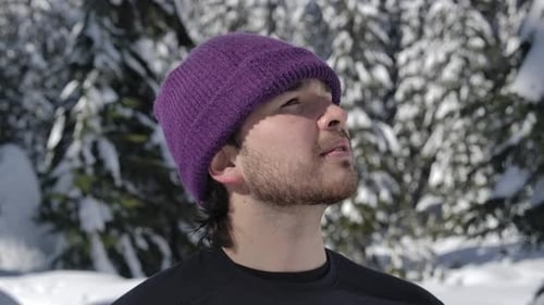 Caucasian Man In Knitted Hat Looking Around At Snowy Forest On Sunny Day. closeup, slow motion