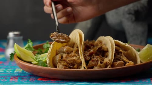 Delicious Tacos on a Plate being drizzled with sauce