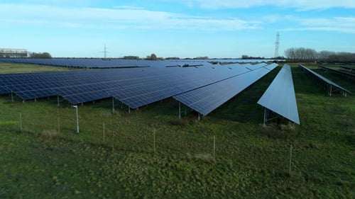 Low-altitude aerial drone view gliding over vast solar power arrays, capturing the rhythmic,