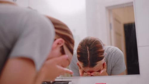 Mujer independiente lavándose la cara en el baño