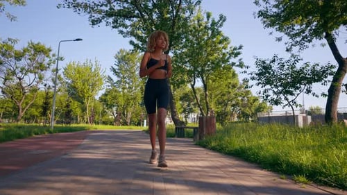 Woman Jogging on a Path in an Urban Park