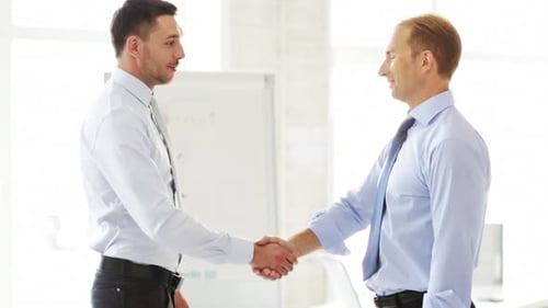 Businessmen shaking hands after successful negotiation in modern office