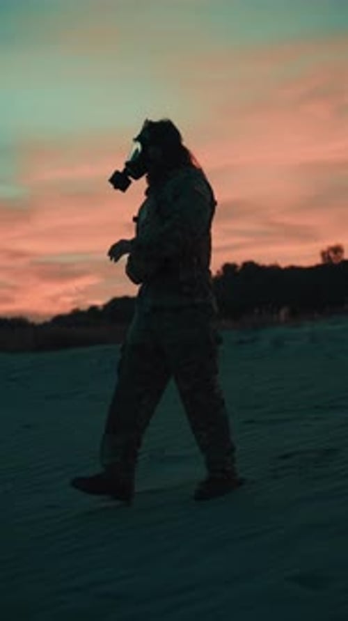 Walking on the Beach Military Silhouette with Gas Mask at Red Sunset
