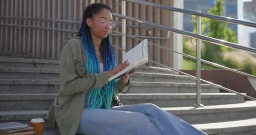 Young Woman Reading Book on Exterior Urban Steps