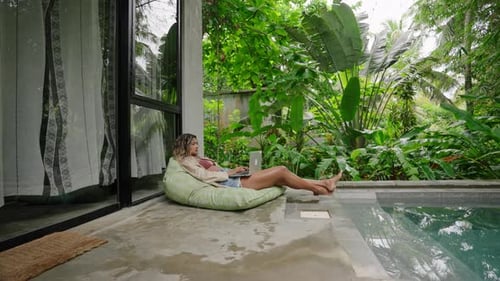 Multiethnic Woman Enjoys Remote Work By Pool in Tropical Garden Relaxed Freelance Lifestyle