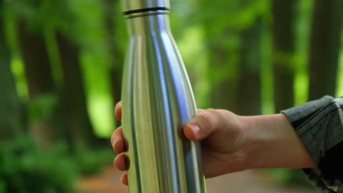Closeup of Unrecognizable Female Hand Holding Water Bottle Reusable Steel Thermo Water Bottle in
