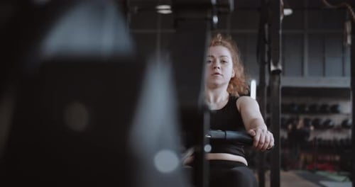 Woman Using Rowing Machine at the Gym