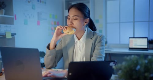 businesswoman happy enjoy eat fast food hamburger in office at night.