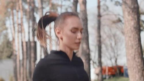Young Woman Warming Up and Exercising with Jump Rope in a Park