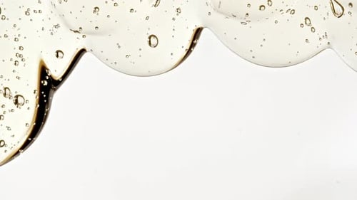 Gel cosmétique fluide transparent avec des bulles de molécules s'écoulant sur la surface blanche