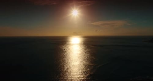 Setting sun above the dark waterscape of the peaceful ocean.