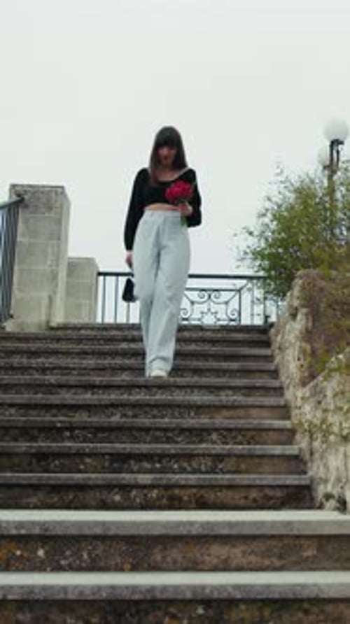 Woman Going Down The Stairs Outdoor In The Small Town With Red Flowers
