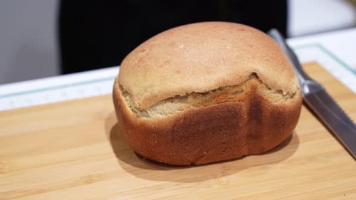 Golden Loaf of Bread on Wooden Cutting Board