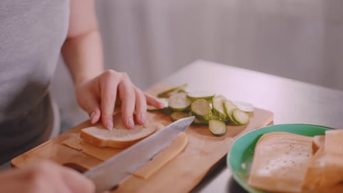 Close Up Cutting Bread with Cheese Beside Fresh Cucumber Slices