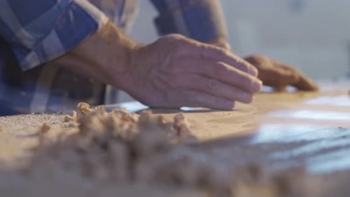 Der Schreiner reinigt die Späne und den Staub vom Holz.