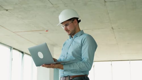 Engineer Analyzing Data on Laptop at Building Site