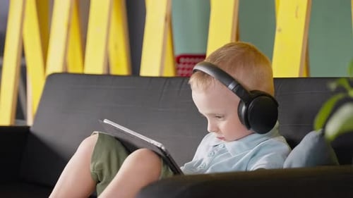 Young Boy on Couch Using Tablet with Headphones