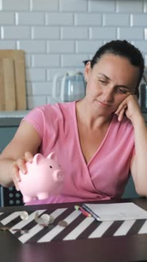 Woman Empties Piggy Bank in Kitchen