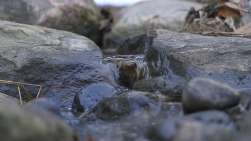 Nahaufnahme von Wasser, das zwischen zwei Felsen in einem kleinen Bach fließt (4K)
