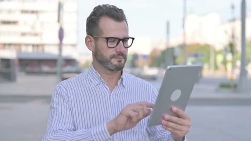 Man Standing Outside Using Silver Tablet