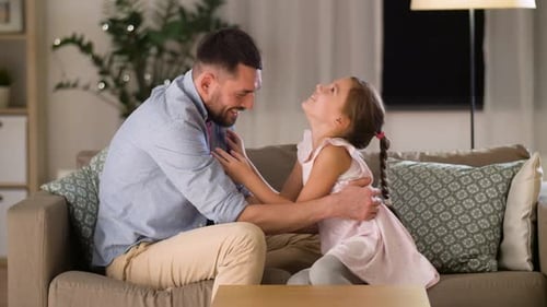 Playful Father and Daughter Playing at Home on Couch
