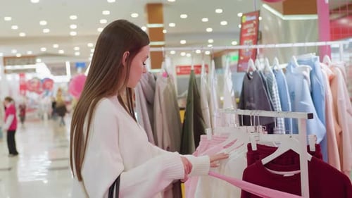Lady Observing Clothes in Mall with Shoppers in Background