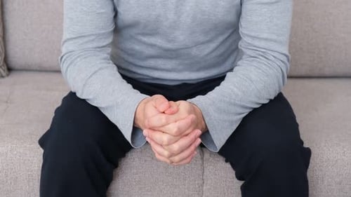 Person Sitting with Hands Clasped