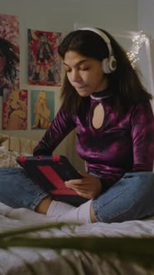 Girl Sits on Bed in Her Room and Surfs Internet Using Tablet
