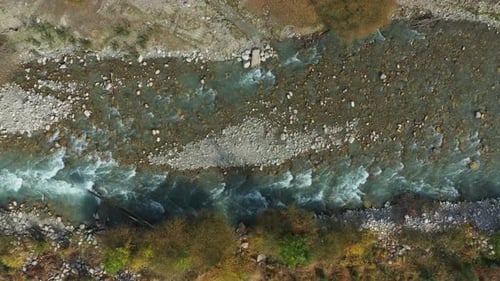 River Water Gracefully Flowing Through a Rugged Rocky Landscape in a Serene Forested Valley