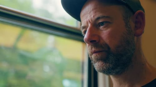 Productive male traveler at window seat on train trip with eyes fixed on laptop