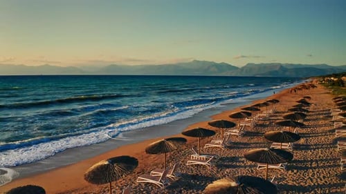 Beautiful sunset at the tropical beach. View of the wooden umbrellas and sun beds at the beach. trop