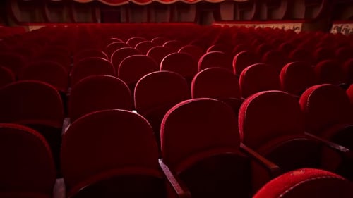Red velvet chairs in theater hall. Rows of comfortable seats without people.