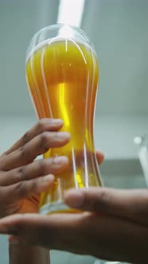 Person Holds Glass of Bright Yellow Beer Close Up