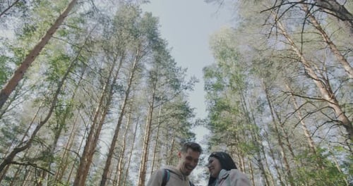 Joyful Young People Standing in Forest Watching Photos in Camera and Talking Enjoying Beautiful View