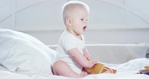 A baby, a boy with large blue eyes and light-colored hair, plays with a wooden airplane toy and sm