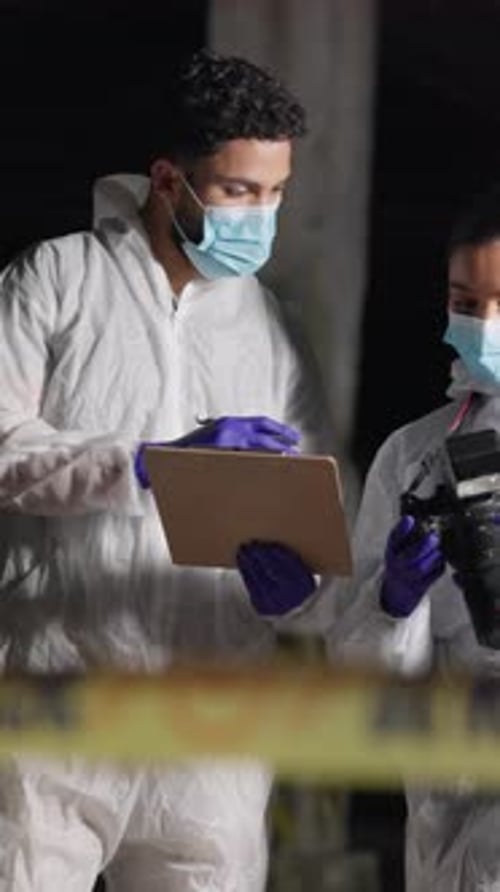 Forense, equipo y portapapeles en la escena del crimen para discusión, proceso legal y cámara por la noche