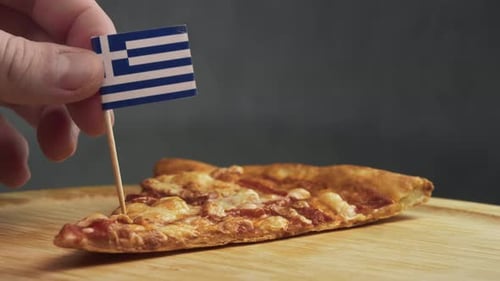 Drapeau grec près du bout d'une tranche de pizza, symbole de la pizza grecque d'inspiration méditerranéenne