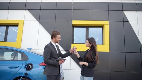 Man dealer with tablet passing car keys to happy owner outdoors