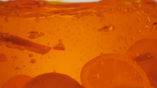 Citrus Slices Dropping into Clear Liquid