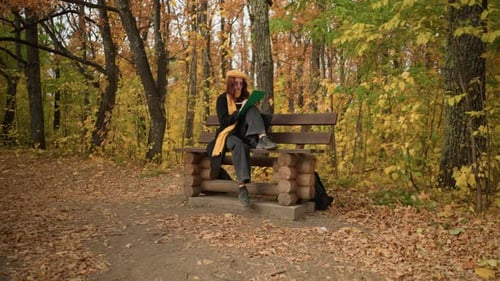 Female Artist Sketching on Wooden Park Bench Surrounded By Autumn Foliage