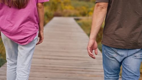 junges Ehepaar, Mann und Frau, gehen Händchen haltend durch den Wald und genießen Schönheit