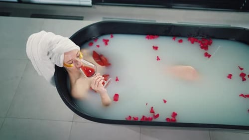 Woman Relaxes in Black Tub with Wine