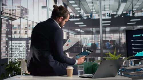 Businessman Analyzing Charts on Desk in Modern Office
