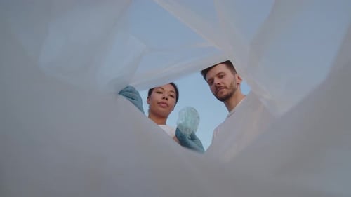 Un hombre y una mujer ponen plástico en una bolsa para limpiar un lugar de basura Grupo de ecoactivistas limpian basura en