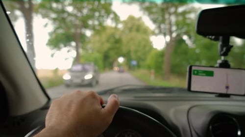 Hand on Steering Wheel Close Up Driving Using GPS Navigation on Smartphone Driver Man in Car Slow